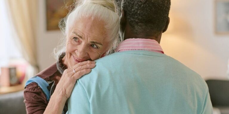 Elderly Woman Hugging Caregiver Warmly in Bright Room at Assisted Living Facility